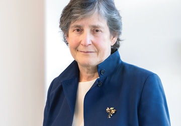 Gray haired woman in blue jacket with brooch