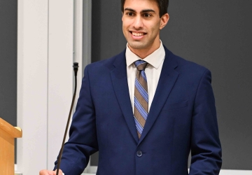 Akesh Shah stands behind a podium.