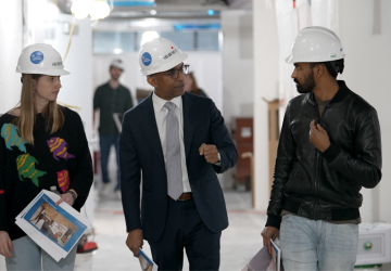 Two. men and a woman in hardhats walking and talking