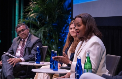 Man and woman panelists listening to woman speak on panel