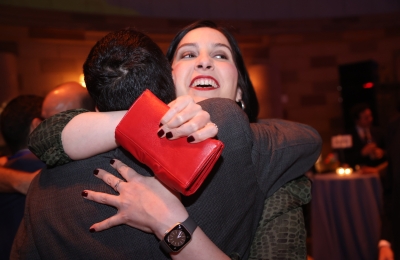 Woman hugging a friend while holding a red clutch