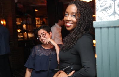 Two women in black dresses smiling at party