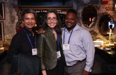 Two men and a women with nametags smile at camera