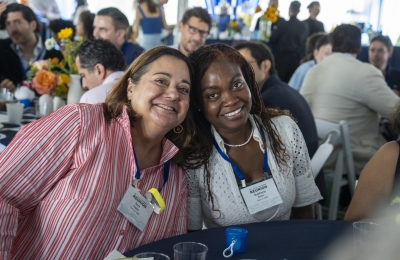 Two women seated, with heads together smiling at camera