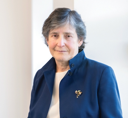 Gray haired woman in blue jacket with brooch