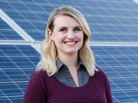 Melanie Scheible ’16 smiles, standing in front of an installation of solar panels.