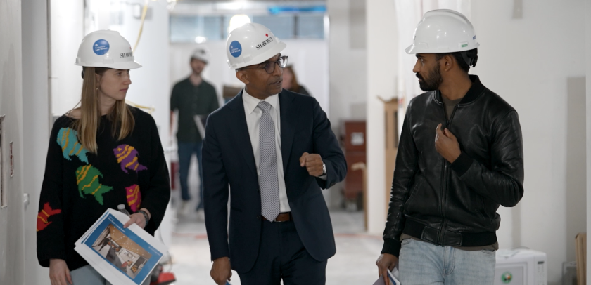 Two. men and a woman in hardhats walking and talking