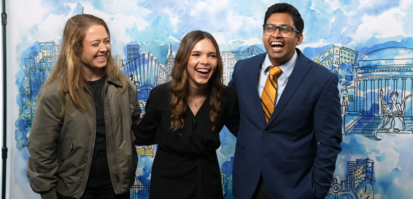 Two women and a man in front of a painted mural