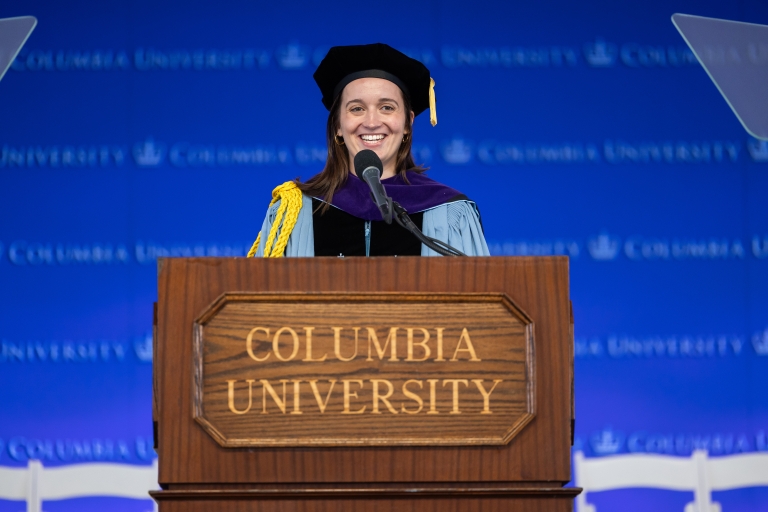 Alix Eichenlaub in academic regalia behind a podium