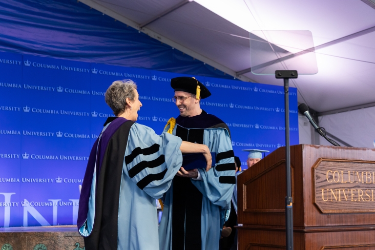 Professor Clare Huntington receives award from student Remington Pool on the graduation stagen