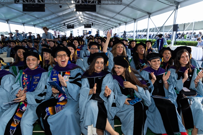 Students in academic regalia cheer their fellows classmates