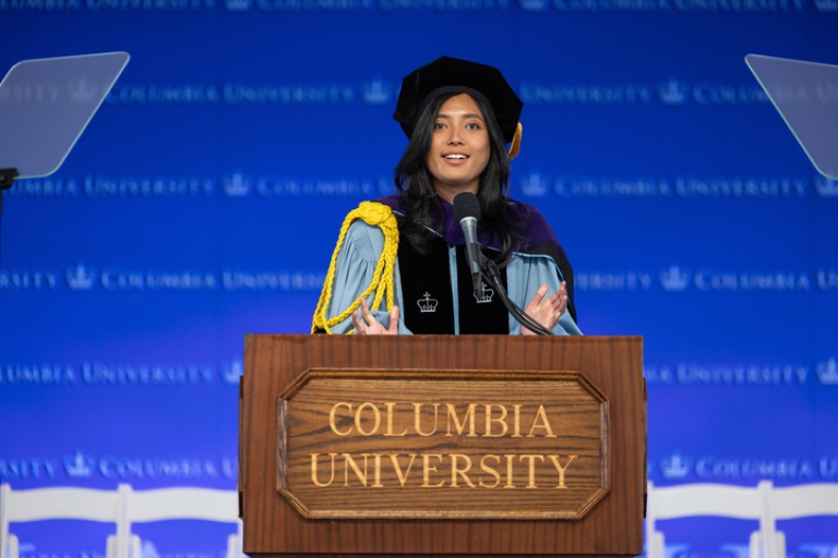 Rabita Madina in academic regalia behind podium