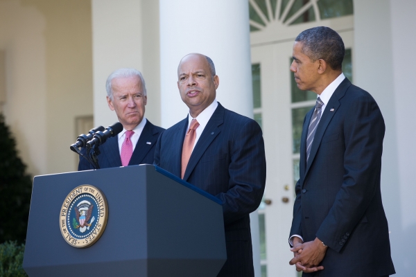 Man at presidential podium flanked by president and vice president