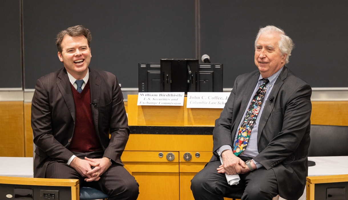 Two men seated, smiling 