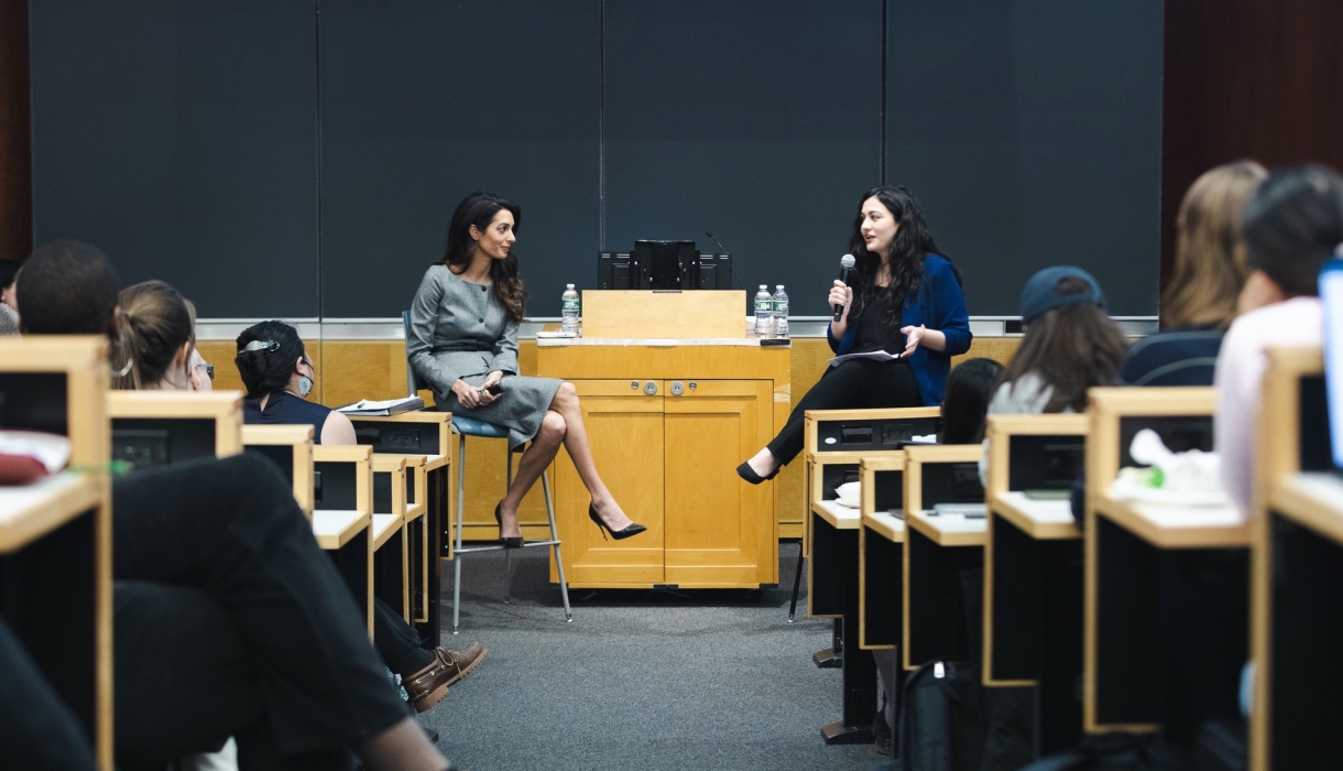 Two women in front of podium speak to an audience