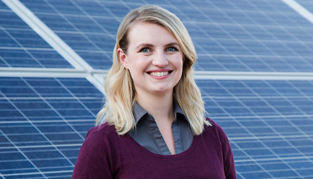 Melanie Scheible ’16 smiles, standing in front of an installation of solar panels.