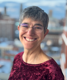 Woman in a red shirt and glasses smiling