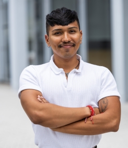 Sebastian Araujo wearning a white polo shirts an folding his arms