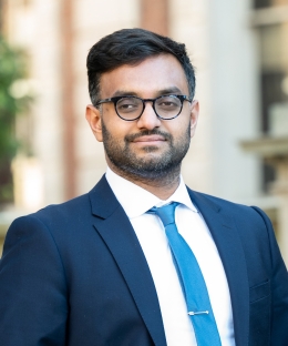 Professor Ashraf Ahmed smiling. He wears glasses with a blue suit and necktie.