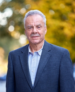 Professor Conrad Johnson stands in front of autumn trees on the Columbia campus.