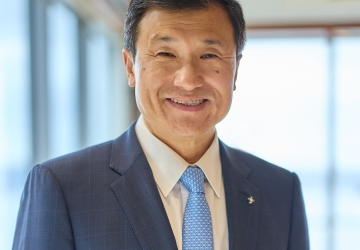 Headshot of a man wearing a blue jacket, white shirt, and blue tie