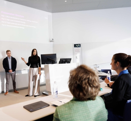 Students in front of a presentation in a classroom, addressing the shark tank judges in the Legal Financial Arbitrage class
