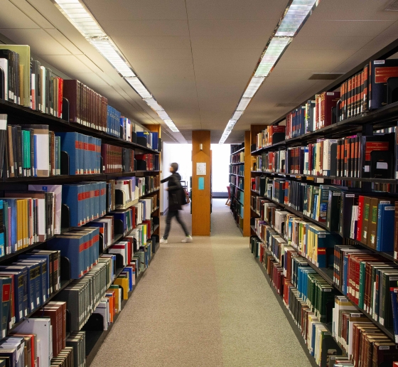 A student walks past a shelf of books in the Diamond Law Library