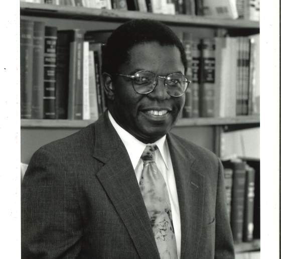 Man in suit and tie holding law book in front of bookshelves