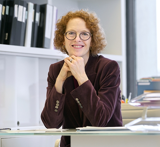 Women with red hair and glasses in her office